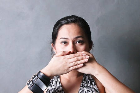 Young woman covering her mouth with both handsの写真素材