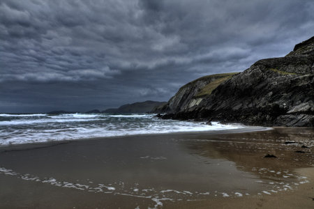 Beat of waves at sandy beach in Dingle peninsula during windy sunsetの写真素材
