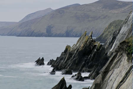 Beat of waves at rocky beach in Dingle peninsula during windy sunsetの写真素材