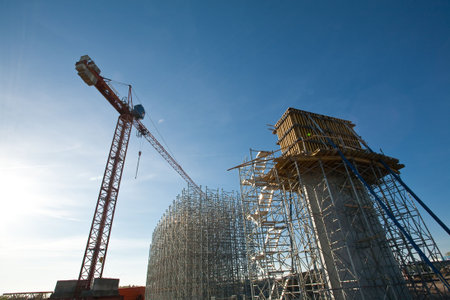 Scafold of bridge and crane against blue sky 