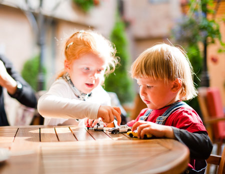 Little boy ant girl playing on table with toy cars