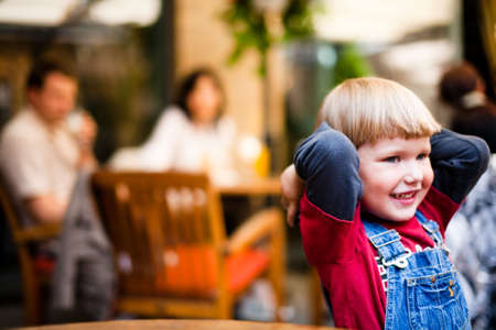 Little boyl playing on table with toy cars parents in background defocusedの写真素材