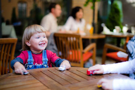 Little boyl playing on table with toy cars parents in background defocusedの写真素材
