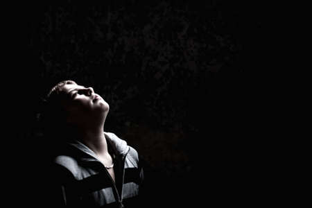 Teenage boy looking up against concrete wall check out more of the same modelの写真素材
