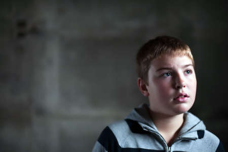 Young boy looking up with hope in his eyes against grunge background flash lit 3 light sourcesの写真素材
