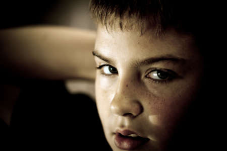 Young boy looking up with hope in his eyes against grunge background flash lit 3 light sourcesの写真素材