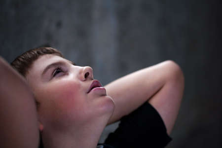 Young boy looking up with hope in his eyes against grunge background flash lit 3 light sourcesの写真素材