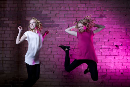 Teenage girl jump in the air against brick wall urban style lit with flashの写真素材