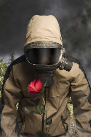 Man in a gas mask looking at a rose の写真素材