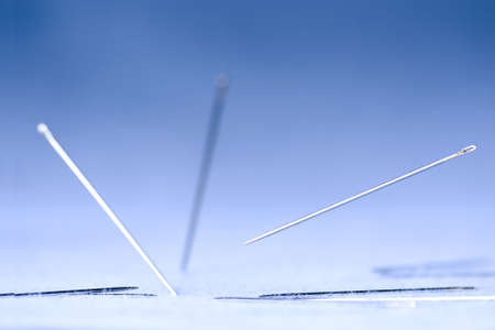 photo of needles falling on blue fabricの写真素材