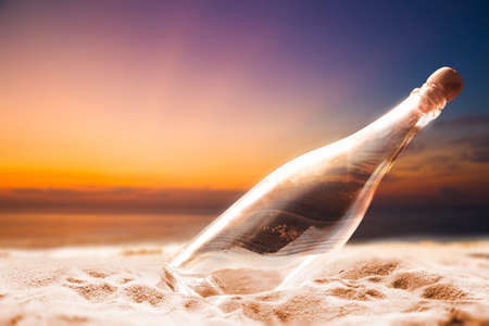 Empty bottle on a shore at sunsetの写真素材