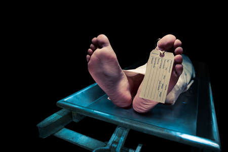 Grungy photo of feet with toe tag on a morgue tableの写真素材