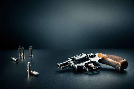 gun sitting on a table with bullet shellsの写真素材