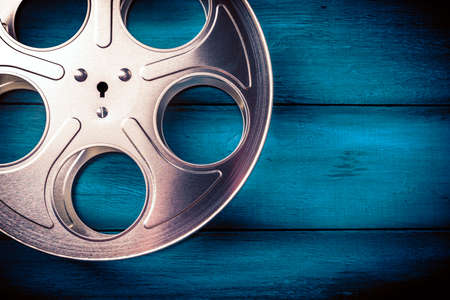 35mm film reel with dramatic lighting on a wooden backgroundの写真素材