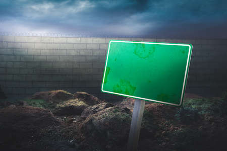border concept with blank sign in front of a high wall and dramatic lightingの写真素材