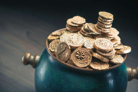 gold coins in a green pot on a dark backgroundの写真素材