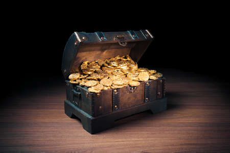 Open treasure chest filled with gold coins / HIgh contrast imageの写真素材