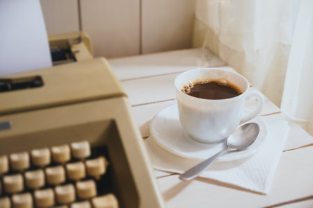 steaming cup of coffee with a vintage type writer machine / selective focus on drink