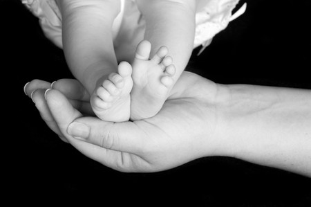 Newborn baby's feet cradled in mother's handの写真素材