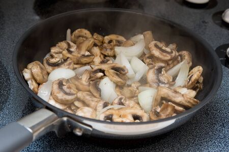 Mushrooms and Onions being sauteed in a frying panの写真素材
