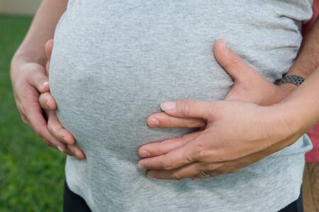 Pregnant Stomach with man and woman's hands holding itの写真素材