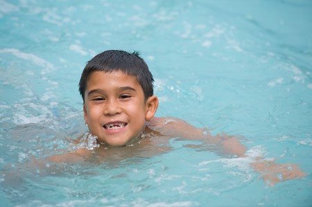 Adorable young brunette boy swimming and smiling in the poolの写真素材