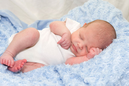 Newborn baby boy sleeping on a blue blanket