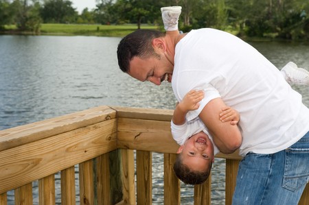 Father holding son upside down playing outdoorsの写真素材