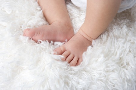 Baby feet on a white carpetの写真素材