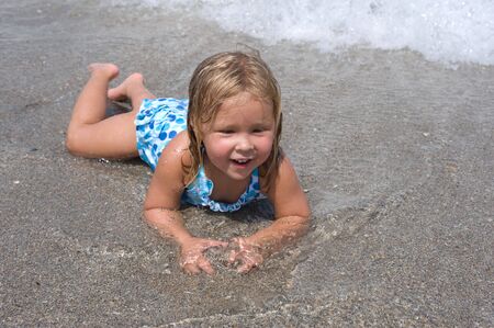Adorable little blond girl having fun at the beach の写真素材
