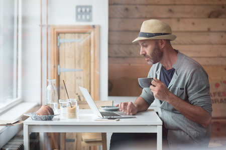 Mid thirties man working on his laptop inside a cafe
