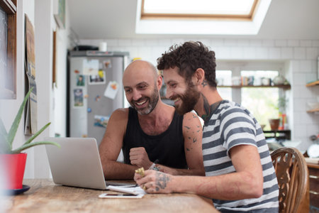 Gay couple using laptop in the kitchenの写真素材