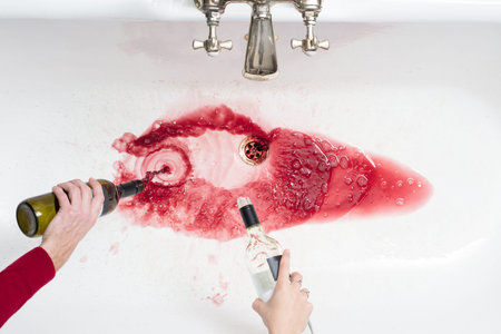 Detail of a couple pouring away wine in an act of giving up alcoholの写真素材