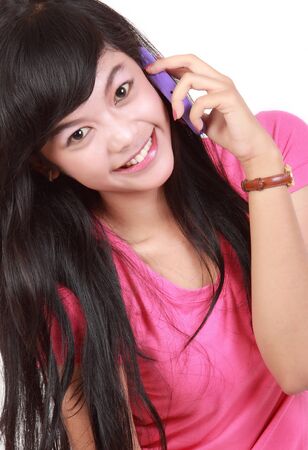Closeup of beautiful young girl smiling during phone call on white backgroundの写真素材