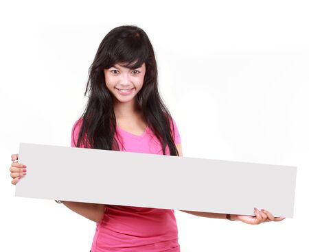 Portrait of a cute young woman holding a long blank board for your text againts white backgroundの写真素材