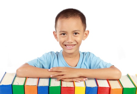 portrait of young boy smiling on top of his colorful books isolated over white backgroundの写真素材