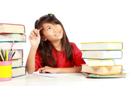 cute little girl thinking something while studying isolated on whiteの写真素材