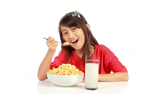 little girl having breakfast isolated on white backgroundの写真素材