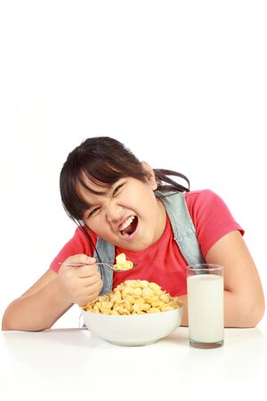 little girl having breakfast with milk isolated on white backgroundの写真素材