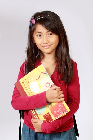 Portrait of girl smiling with backpack and holding booksの写真素材
