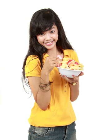young healthy girl having a fruit salad. isolated on whiteの写真素材