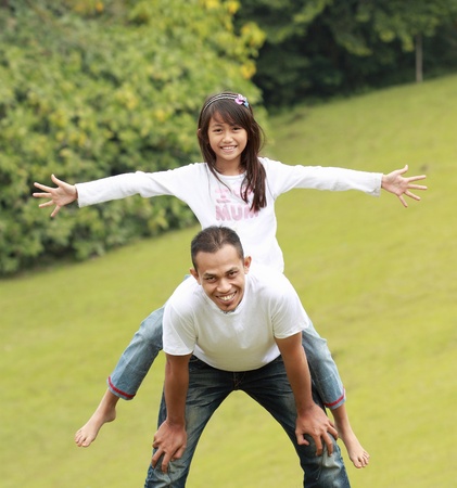 Father giving daughter piggyback ride outdoors smilingの写真素材