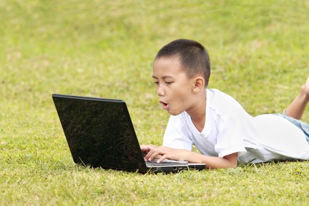 Shocked kid on laptop in the gardenの写真素材
