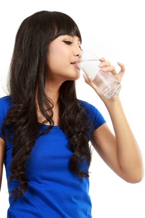 Beautiful young girl drinks water from glass - in isolated white backgroundの写真素材