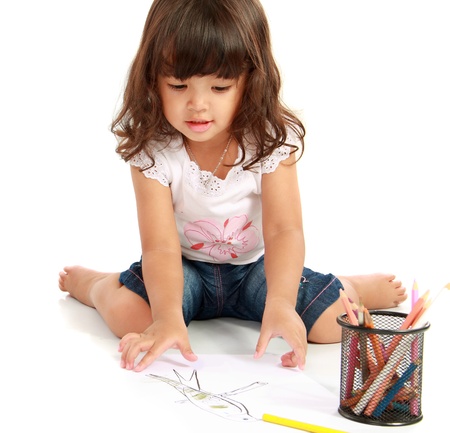 little pretty girl drawing and coloring with pencil color on a white backgroundの写真素材