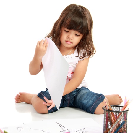 little pretty girl looking at her artwork on white backgroundの写真素材