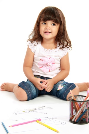 little cute girl smiling while draw with pencil color on a white backgroundの写真素材