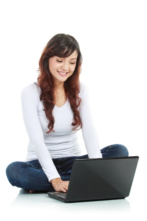 Young female sitting cross-legged on floor with laptop isolated white backgroundの写真素材