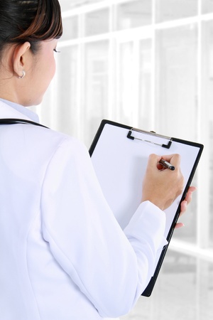 Potrait of female doctor writing on clipboard, back viewの写真素材