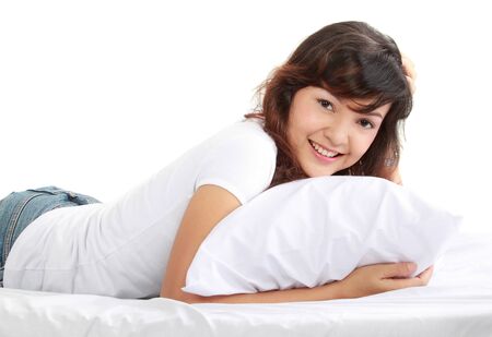 portrait of a happy young asian woman lying on the bedの写真素材